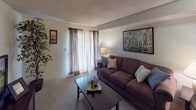 Located at 5001 College St SE in Lacey, Washington, this ground-floor unit offers a practical and comfortable single-level layout. The living area is warm and inviting, featuring soft carpeting, a textured ceiling, and a large window dressed with sheer curtains that allow natural light to fill the room. A nature-inspired wall painting adds a touch of character to the space, which flows seamlessly into a dedicated dining area — ideal for everyday living and entertaining. The galley-style kitchen is efficiently designed with ample white cabinetry lining both sides, providing generous storage and counter space. It is equipped with a full suite of appliances including a range, refrigerator, dishwasher, and microwave, all set over easy-to-clean tile flooring. The bedroom is spacious and serene, with plush carpeting, a textured ceiling, and a window with blinds that offer privacy and light control. A large sliding-door closet provides substantial storage, while the room comfortably accommodates full bedroom furnishings. The unit's straightforward, single-floor layout ensures easy navigation throughout, making it a practical and welcoming residence in the heart of Lacey.