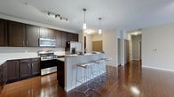 Located at 26600 George Zeiger Dr in Beachwood, OH, this well-appointed 2-bedroom, 2-bathroom residence offers a thoughtfully designed single-floor layout. Rich hardwood flooring flows throughout the open-concept living and kitchen areas, creating a warm and cohesive aesthetic. The kitchen is a standout feature, boasting dark espresso cabinetry, stainless steel appliances including a gas range and French door refrigerator, a subway tile backsplash, and granite countertops that extend to a multi-seat breakfast bar illuminated by stylish pendant lighting. The living room is bright and open, benefiting from floor-to-ceiling vertical blinds framing a large sliding glass door that fills the space with natural light. A built-in fireplace adds a refined focal point to the room. The generously sized primary bedroom features plush carpeting, a ceiling fan, and a large window, complemented by an expansive walk-in closet with custom dark wood shelving and dual hanging rods. The primary bathroom offers a granite vanity, dark cabinetry, a glass-enclosed shower, and a soaking tub with tile surround. The second bedroom is carpeted and well-proportioned. This residence combines modern finishes with functional design throughout.