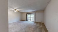 This 2-bedroom, 2-bathroom single-floor residence offers a functional and comfortable layout across a well-utilized footprint. The open-concept living, dining, and kitchen area serves as the heart of the home, featuring plush wall-to-wall carpeting, a ceiling fan with light fixture, and a textured ceiling. A sliding glass door opens to a private balcony overlooking lush tree canopy, filling the space with natural light and greenery views.

The kitchen is equipped with warm wood-toned cabinetry, a double-basin sink, a dishwasher, and a full-size refrigerator, complemented by a tile floor and an adjacent pantry for additional storage.

The primary bedroom is generously sized, featuring carpet flooring, a window with outdoor views, and direct sliding door access to the balcony. The second bedroom also offers carpet flooring and a window with natural light. Both bedrooms are supported by well-appointed closets with wire shelving systems, and the unit includes a total of four closets throughout.

The two full bathrooms each feature a tub-shower combination, tile flooring, and vanity with storage. A dedicated laundry area and a hallway connecting the rooms round out the practical layout of this thoughtfully designed residence.