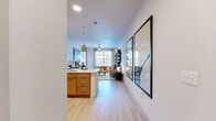 This thoughtfully designed one-bedroom, one-bathroom residence offers an efficient and stylish single-floor layout that maximizes every square foot. Light wood-style flooring flows throughout the main living areas, creating a cohesive and airy feel. The open-concept kitchen and living area form the heart of the home, where warm honey-toned cabinetry, a white quartz countertop island with bar seating, and stainless steel appliances — including a range, microwave, and refrigerator — combine functionality with contemporary style. Pendant lighting above the island adds a modern accent. The living room is bright and welcoming, benefiting from large windows that invite natural light and offer outdoor views, complemented by a ceiling fan overhead. The bedroom is a comfortable retreat featuring a generous window, light-filtering blinds, and access to a well-organized walk-in closet. The bathroom includes a soaking tub with shower, tile flooring, and warm wood vanity cabinetry. Additional closet storage is plentiful throughout, with four dedicated closet spaces in total. A dedicated entrance and hallway provide a smooth transition into the living areas, rounding out this clean, modern, and efficiently planned residence.