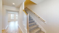 Located at 4104 Maycomb Cypress in College Station, TX, this two-story home offers four bedrooms and four full bathrooms across two well-proportioned floors. The main level features an open-concept kitchen and living area with light hardwood-style flooring throughout. The kitchen is a standout, boasting a large white quartz island with an integrated sink, dark espresso cabinetry, stainless steel appliances, and an industrial-style pendant light fixture. The living area features a decorative board-and-batten accent wall and recessed lighting, with an entryway framed by a distinctive navy blue front door. Upstairs, the bedrooms are finished with plush carpeting and ceiling fans, each with access to well-appointed bathrooms. The bathrooms feature white quartz countertops, slate-blue vanities with matte black hardware, and tiled tub-shower combinations. Select bedrooms include walk-in closets with built-in shelving. The primary bedroom offers a connected bathroom with a dedicated walk-in closet. Outside, a fully fenced backyard provides a private, grassy outdoor space with a young shade tree, ideal for relaxation or entertaining.