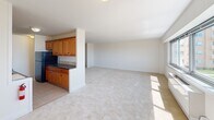 Located along the Long Branch coastline, this 2-bedroom, 2-bathroom residence offers an impressive blend of comfortable living and breathtaking oceanfront scenery. The open living area is generously proportioned, featuring neutral carpet flooring, bright white walls, and a wide picture window that frames sweeping views of the Atlantic Ocean and the community pool and grounds below. The layout flows seamlessly from the living space into the kitchen, which is outfitted with warm honey-toned wood cabinetry, dark countertops, tile flooring, and black appliances. A private balcony accessible from the main living area extends the living space outdoors, providing unobstructed views of the ocean and surrounding landscape. The spacious primary bedroom includes a dedicated closet and an en-suite bathroom, while the second bedroom features its own window with views and ample natural light. Both bathrooms are finished with elegant beige tile work accented by decorative mosaic border strips — one featuring a walk-in shower with grab bars, and the other a full soaking tub and shower combination. A hallway and additional closet provide practical storage throughout. Soft carpet runs through all living and sleeping areas, contributing to the home's warm, coastal ambiance.