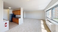 Located along the Long Branch coastline, this 2-bedroom, 2-bathroom residence offers an impressive blend of comfortable living and breathtaking oceanfront scenery. The open living area is generously proportioned, featuring neutral carpet flooring, bright white walls, and a wide picture window that frames sweeping views of the Atlantic Ocean and the community pool and grounds below. The layout flows seamlessly from the living space into the kitchen, which is outfitted with warm honey-toned wood cabinetry, dark countertops, tile flooring, and black appliances. A private balcony accessible from the main living area extends the living space outdoors, providing unobstructed views of the ocean and surrounding landscape. The spacious primary bedroom includes a dedicated closet and an en-suite bathroom, while the second bedroom features its own window with views and ample natural light. Both bathrooms are finished with elegant beige tile work accented by decorative mosaic border strips — one featuring a walk-in shower with grab bars, and the other a full soaking tub and shower combination. A hallway and additional closet provide practical storage throughout. Soft carpet runs through all living and sleeping areas, contributing to the home's warm, coastal ambiance.