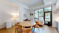 Located at 527 Minor Ave N in Seattle's Lower Queen Anne neighborhood, this well-appointed one-bedroom, one-bathroom unit offers a thoughtfully designed single-floor layout with a clean, modern aesthetic throughout. The open-concept living and dining area serves as the heart of the home, featuring warm hardwood floors, recessed lighting, and large sliding glass doors that invite natural light. A round wood dining table surrounded by curved leather chairs adds a stylish focal point, while a comfortable sofa anchors the living space. The kitchen is fully equipped with sleek flat-front cabinetry in a soft blue-grey tone, stainless steel appliances including a gas range and dishwasher, a subway tile backsplash, and ample counter space — all flowing seamlessly into the main living area. A sliding barn door leads to the hallway, adding a contemporary architectural detail. The bedroom is a calm, carpeted retreat with crisp white walls, soft neutral furnishings, and warm accent lighting. The full bathroom features hardwood flooring, a white vanity with an undermount sink, a bathtub with shower, and clean white finishes throughout. This unit combines functional design with modern comfort in a highly walkable Seattle location.
