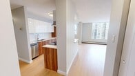 Located in Calgary, AB, this thoughtfully designed 2-bedroom, 1-bathroom unit offers a clean, contemporary aesthetic throughout. Light oak-toned hardwood flooring flows seamlessly across all living areas, complementing the neutral grey and white color palette that lends the space a bright, modern feel.

The kitchen is a standout feature, showcasing a striking combination of high-gloss white upper cabinetry and rich wood-grain lower cabinetry. A peninsula with a stone countertop provides additional prep space and casual seating. Stainless steel appliances, including a dishwasher and refrigerator, complete the well-equipped kitchen.

The open-concept layout connects the kitchen to a generously sized living area, which benefits from large windows that flood the room with natural light and offer views of the surrounding Calgary cityscape. Baseboard heating runs along the perimeter of the living space and bedrooms.

Both bedrooms are comfortably sized, each featuring large windows with city views and light hardwood flooring. The primary bedroom includes a built-in sliding door closet for practical storage. The second bedroom offers a similarly bright and airy feel.

The bathroom is finished in a clean, minimalist style with white tile flooring, a full-width vanity mirror, white cabinetry, and modern fixtures.