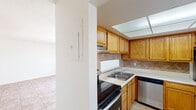 Summit West Two Bedroom B1 – Unit 19C is a well-laid-out single-floor residence designed for comfortable everyday living. The kitchen is a functional highlight of the unit, featuring warm oak cabinetry with ample upper and lower storage, light-toned countertops, a double-basin stainless steel sink, and a diamond-pattern tile backsplash. Stainless steel appliances — including a refrigerator, dishwasher, and range — complement the space, while a drop-ceiling light panel provides bright, even illumination. Light tile flooring runs throughout the kitchen and into the main living area. The living room is open and airy, bathed in natural light from large sliding glass doors fitted with vertical blinds that lead to an outdoor patio area. A ceiling fan adds comfort, and a built-in shelf niche provides a subtle architectural detail. The bedrooms are finished with soft carpeting and feature windows with vertical blinds, offering a quiet and comfortable retreat. The bathroom is clean and straightforward, equipped with a tub-shower combination accented by white tile surround, a single vanity with oak cabinetry, a large mirror, and Hollywood-style lighting. The overall ambiance of the unit is bright, neutral, and move-in ready.