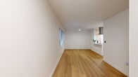 This 490 square foot apartment in Seattle offers a thoughtful blend of comfort and functionality within a compact footprint. The single-floor layout comprises one bedroom, one bathroom, and an open-concept kitchen and living area. 

The space is characterized by its modern aesthetic, featuring crisp white walls that create a bright, airy atmosphere. Large windows with horizontal blinds allow for abundant natural light and glimpses of the urban surroundings. The flooring throughout is a warm, honey-toned hardwood that adds warmth and continuity to the space.

The kitchen is a standout feature, boasting a sleek design with a mix of white upper cabinets and light wood lower cabinets. A curved peninsula with a built-in cooktop creates a functional cooking area and provides additional counter space. Stainless steel appliances, including a refrigerator and built-in microwave, complete the modern culinary setup.

The bedroom, measuring 120 square feet, offers a cozy retreat with a large window for natural light. The bathroom is efficiently designed with a shower/tub combination, a wooden vanity, and continues the apartment's clean, modern aesthetic.

Despite its compact size, the apartment feels spacious due to its thoughtful layout and use of light colors. Built-in storage solutions and minimalist fixtures contribute to the overall sense of openness and functionality, making this Seattle apartment an ideal urban dwelling for those seeking a stylish yet efficient living space.