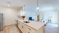 Located at 3883 E Market St in York, PA, this thoughtfully designed one-bedroom, one-bathroom unit offers a clean, modern aesthetic across a single floor. The open-concept kitchen is a standout feature, boasting white shaker cabinetry with matte black hardware, quartz countertops, a tile backsplash, stainless steel appliances including a range, microwave, dishwasher, and refrigerator, and pendant lighting over a generous island with a single-basin sink. Light hardwood flooring runs throughout the main living areas, lending warmth and continuity to the space. A dedicated laundry area with a full-size washer and dryer is conveniently tucked within the kitchen corridor, alongside a pantry for additional storage. The living room is bright and airy, featuring elevated ceilings and a sliding glass door that opens to a private patio with outdoor views. The bedroom offers plush carpeting, a double-door closet, and dual windows that fill the room with natural light. The bathroom includes a white vanity with ample storage, wood-look tile flooring, and a full tub-shower combination. With three closets and a hallway connecting the spaces, this unit offers practical storage and a well-organized layout suited for comfortable everyday living.