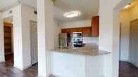 This single-floor residence offers a thoughtfully designed layout that balances comfort and functionality. The entry foyer welcomes you with warm hardwood-style flooring and clean white walls, setting the tone for the rest of the home.

The kitchen is a standout feature, showcasing rich warm-toned cabinetry, granite countertops, and a classic white subway tile backsplash. A peninsula with an integrated sink provides additional prep space and casual seating potential, while a full suite of stainless steel appliances—including a refrigerator, range, microwave, and dishwasher—completes the space.

The living area is generously proportioned, featuring plush carpeting, crown molding details, a ceiling fan, and an elegant arched doorway that leads to the kitchen. Sliding glass doors open onto a private balcony, allowing natural light to fill the room while offering pleasant outdoor views.

The bedrooms are carpeted and finished with ceiling fans and windows that bring in natural light. The bathroom features a granite-topped vanity with rich wood cabinetry and a large mirror, providing ample storage and a polished aesthetic.

A dedicated in-unit laundry room with full-size washer and dryer and built-in shelving adds everyday convenience, rounding out this well-equipped and cohesive living space.