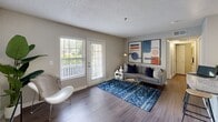 Located at 3400 Cox Road in Richmond, VA, this one-bedroom, one-bathroom residence offers a thoughtfully designed single-level layout that maximizes every square foot of its compact footprint. The open-concept living and dining area is anchored by wood-style flooring and features large windows with exterior door access, allowing abundant natural light and views of the surrounding greenery to fill the space. The combined area provides comfortable room for both a seating arrangement and a dining set.

The galley-style kitchen is efficiently laid out with white cabinetry, granite-look countertops, a full suite of appliances including a stainless microwave, and direct access to a dedicated in-unit laundry room equipped with a full-size washer and dryer — a notable convenience.

The bedroom is a calm, well-proportioned retreat with dual windows that frame outdoor greenery, wood-style flooring, and neutral gray walls that create a restful ambiance. A hallway closet provides additional storage.

The bathroom features a white vanity with granite countertops, an undermount sink, and a well-lit mirror — combining clean, modern finishes with everyday functionality. Throughout the residence, consistent neutral tones, textured ceilings, and warm flooring create a cohesive and inviting atmosphere.