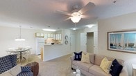 Located at 4632 Still Meadow Dr in Wilmington, this single-floor residence offers a comfortable and functional layout designed for easy living. The open-concept living and kitchen area forms the heart of the home, creating a seamless flow between spaces. The living area is finished with plush wall-to-wall carpeting and is anchored by a ceiling fan with an integrated light fixture, providing both comfort and illumination. A textured ceiling adds subtle character throughout the space. The kitchen is positioned adjacent to the living area and is separated by a raised breakfast bar, ideal for casual dining or entertaining. It features white appliances, including a full-sized refrigerator and range, complemented by warm wood-toned upper cabinetry that adds a touch of warmth to the space. Recessed and overhead lighting ensures the kitchen remains bright and practical. A closet with louvered doors is conveniently accessible from the main living area, offering generous storage. The neutral color palette throughout the home — featuring soft whites and warm beiges — creates a clean, inviting ambiance that is easy to personalize. The single-floor layout ensures accessibility and convenience for everyday living.