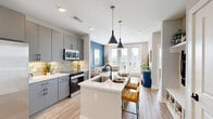 Located on Wilkinson Boulevard in Charlotte's west side, this one-bedroom, one-bathroom unit offers a thoughtfully designed layout that maximizes its compact footprint. Light wood-style flooring runs throughout, creating a cohesive, contemporary feel across every room.

The open-concept living and kitchen area serves as the heart of the unit. Large floor-to-ceiling windows and French doors flood the living space with natural light while framing impressive views of the Charlotte skyline. A bold blue accent wall adds a striking visual element, complementing the neutral tones throughout. The kitchen features sleek gray cabinetry extending to the ceiling, white countertops, a tiled backsplash, and stainless steel appliances, offering both style and functionality. A built-in shelf and hook wall near the entry provides practical organization.

The bedroom is generously proportioned, featuring a ceiling fan, large windows with skyline views, and a calming gray accent wall. It connects directly to the full bathroom, which includes tile flooring, marble-style tiled walls, and direct access to a dedicated closet outfitted with built-in shelving and hanging storage.

The overall ambiance is bright, modern, and inviting, with a consistent design language that balances comfort and urban sophistication.