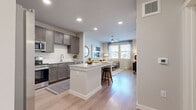 This thoughtfully designed one-bedroom, one-bathroom residence offers an efficient and functional layout across a single floor. The open-concept kitchen and living area serves as the heart of the space, anchored by a central island with granite countertops and bar seating — ideal for casual dining or entertaining. The kitchen is equipped with rich, dark-toned cabinetry, stainless steel appliances including a refrigerator, range, and microwave, and a classic white subway tile backsplash that adds a crisp, contemporary contrast. Light wood-style flooring flows seamlessly throughout, unifying each area of the home. The living room is bright and inviting, benefiting from multiple windows that allow generous natural light and views of the surrounding greenery. A ceiling fan overhead adds both function and style. The bedroom is a comfortable retreat, featuring dual windows, a ceiling fan, and access to a dedicated closet. The bathroom is well-finished with dark cabinetry, granite countertops, a single vanity, and a tiled shower-tub combination. A hallway connects the private sleeping quarters to the main living areas, adding a sense of separation and privacy. Overall, the space presents a clean, modern aesthetic with warm, neutral tones throughout.