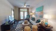This single-story residence offers a thoughtfully designed layout across two bedrooms and two bathrooms. The living room serves as the heart of the home, featuring dark hardwood-style flooring, a ceiling fan, and French doors that open to a private balcony, allowing natural light to fill the space. The room is generously proportioned, providing ample space for comfortable seating arrangements.

The kitchen is outfitted with rich dark cabinetry, granite-style countertops, stainless steel appliances including a refrigerator, range, and built-in microwave, and a stylish tile backsplash. Adjacent to the kitchen, the dining area features track lighting and neutral walls that create an intimate yet functional space.

Both bedrooms offer plush carpeting, ceiling fans, and windows with outdoor views. The primary bathroom features an L-shaped vanity with dark cabinetry, granite-style countertops, and a large mirror, while the secondary bathroom includes a tub-shower combination with tile surround and light tile flooring. The overall design palette of neutral tones, dark wood accents, and consistent finishes throughout gives this residence a cohesive and modern aesthetic.