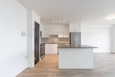 Located at 7 Jackes Ave in Toronto's desirable Summerhill neighbourhood, this one-bedroom, one-bathroom unit offers a well-designed layout across a single floor. Light-toned laminate flooring runs throughout, complementing the crisp white walls and creating a clean, contemporary aesthetic.

The open-concept living area is a standout feature, anchored by expansive floor-to-ceiling sliding glass doors that lead to a private balcony. These large windows flood the space with natural light and frame sweeping views of the Toronto skyline. The kitchen is thoughtfully appointed with white cabinetry, a dark-topped island for additional prep and dining space, stainless steel appliances including a French door refrigerator and electric range, and under-cabinet lighting.

The bedroom is a comfortable size, featuring its own floor-to-ceiling window with balcony access and city views, along with a built-in closet fitted with mirrored sliding doors. The bathroom is finished with classic white subway tile surrounding a full soaker tub and shower combination with chrome fixtures, adding a timeless, polished look. The unit's entryway provides a practical transition into the open living space, completed with a bold dark entry door.