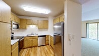 Located on Wildwood Drive in Menomonee Falls, Wisconsin, this single-floor, three-bedroom, two-bathroom home offers a practical and comfortable layout. The kitchen is well-appointed with light oak cabinetry providing ample storage, stainless steel appliances including a refrigerator, dishwasher, and range with over-the-range microwave, and durable hardwood-style flooring that adds warmth to the space. Two bathrooms serve the home: one features a walk-in glass-door shower with a wood-accented medicine cabinet and tile flooring, while the second offers a full tub-shower combination with an oak vanity and matching tile floors. The generously sized primary bedroom includes vaulted ceilings, soft carpeting, and a sliding glass door that opens to a private balcony overlooking lush greenery. A spacious walk-in closet with built-in wire shelving and hanging rods provides excellent storage. The additional bedrooms are carpeted and bright, each benefiting from natural light through large windows with outdoor views. One secondary bedroom features a ceiling fan and a sliding-door closet. Throughout the home, neutral tones and warm wood accents create a clean, cohesive aesthetic.