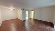 This single-floor residence offers a clean, functional layout with consistent rich, dark hardwood flooring flowing throughout the main living areas and bedrooms. The open living space is bright and airy, highlighted by a ceiling fan and large sliding glass doors dressed with vertical blinds that invite abundant natural light and provide outdoor views. A second window in the bedroom further enhances the natural light throughout.

The kitchen is well-equipped, featuring warm honey-toned wood cabinetry, white countertops, a stainless steel gas range, over-the-range microwave, refrigerator, and dishwasher. A skylight overhead adds an extra dimension of brightness to the cooking space, while light tile flooring completes the look.

The bedrooms are comfortably sized with matching hardwood floors, clean white walls, and ample closet space, including a walk-in closet with built-in shelving in one bedroom. Two updated bathrooms serve the unit: one includes a combination tub and shower enclosed by sliding glass doors with elegant stone-look tile surround and mosaic accent strips, while the second features a standalone walk-in shower with the same refined tile finishes, both complemented by warm wood vanities and light stone tile flooring.