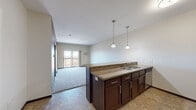 Located at 1290 County Road F W in Arden Hills, Minnesota, this one-bedroom, one-bathroom residence offers a thoughtfully designed single-floor layout that makes efficient use of its cozy footprint. The open-concept kitchen and living area serves as the heart of the home, where rich dark cabinetry, granite-look countertops, and stainless steel appliances — including a refrigerator, range, and built-in microwave — create a functional and attractive cooking space. Pendant lighting above the kitchen peninsula adds a warm, inviting ambiance. The living room flows seamlessly from the kitchen and is finished with plush carpeting, leading to a sliding glass door that opens to a private balcony overlooking an open, natural landscape. The bedroom is a comfortable retreat featuring carpeted floors, a ceiling fan, and a window that draws in natural light and outdoor views. Two closets provide ample storage, including a spacious walk-in closet with double wire-rack shelving. The bathroom is finished with tile flooring, dark cabinetry with a vanity, and a full tub-shower combination. Baseboard heating is present throughout, and the tile flooring in the kitchen and bathroom areas complements the overall neutral, modern color palette of the home.