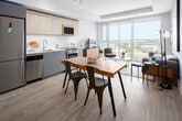 Located on the 14th floor at 299 Campbell Ave in Toronto's vibrant West End, this modern unit offers a thoughtfully designed open-concept layout. A bright hallway with light hardwood flooring and recessed lighting leads into the main living area, where expansive floor-to-ceiling windows frame sweeping panoramic views of the Toronto skyline and surrounding neighbourhoods, flooding the space with abundant natural light.

The living area is well-proportioned, featuring light hardwood floors and a neutral palette that creates a clean, contemporary ambiance. The kitchen is efficiently designed with light wood cabinetry extending to the ceiling, white quartz countertops, a subway tile backsplash, and a full suite of stainless steel appliances including a refrigerator, electric range, built-in microwave, and dishwasher.

The bedroom, visible in the floor plan, is neatly tucked away for privacy, complementing the open living and kitchen zone. The bathroom is finished in a minimalist style with large-format porcelain floor tiles, a light wood vanity with an integrated sink, a wall-mounted storage cabinet, and a frameless glass-enclosed shower. Throughout the unit, the consistent use of white walls, soft neutrals, and natural wood tones creates a cohesive, modern aesthetic well-suited to urban living.