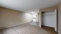 This one-bedroom, one-bathroom unit in Detroit, Michigan offers a straightforward single-floor layout designed for comfortable everyday living. The living area is finished with wall-to-wall carpet and neutral beige walls, creating a warm and inviting atmosphere. A large window dressed with vertical blinds allows natural light to fill the space, while a baseboard heating unit ensures year-round comfort. Built-in white shelving and cabinetry along one wall provide convenient storage and display options, complemented by a bifold-door closet offering additional organization.

The galley-style kitchen features cream-colored upper and lower cabinetry, a wood-toned countertop with an integrated sink, a freestanding electric range, and a full-size refrigerator, all set on durable hardwood-style flooring. The bedroom is a well-proportioned, carpeted room with neutral walls and direct access to the rest of the unit. The full bathroom includes tile flooring, a tiled tub-and-shower combination, a white vanity with sink, and a medicine cabinet mirror, maintaining a clean and functional aesthetic throughout. The unit's cohesive neutral palette and practical layout make it a functional Detroit residence.