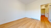 Located at 425 Fourth Street in Gananoque, Ontario, this thoughtfully designed 2-bedroom, 1-bathroom residence offers a clean and modern aesthetic throughout its single floor. Light-toned hardwood flooring flows consistently across all rooms, lending warmth and cohesion to the space.

The two bedrooms are well-proportioned, each featuring crisp white walls, modern black-hardware doors, and baseboard heating. The primary bedroom is generously sized and includes a sliding mirrored closet, while the second bedroom benefits from a large black-framed window that frames lush, tree-lined outdoor views and fills the room with natural light. One bedroom also features a full-width sliding glass door that opens to a private balcony overlooking greenery, adding an appealing indoor-outdoor connection.

The bathroom is finished in an all-white palette, featuring large-format wall tiles, a full soaker tub with shower, and polished chrome fixtures, creating a clean and functional space.

A kitchen with light wood cabinetry and a standard layout is visible in the dollhouse view, complementing the overall neutral and contemporary tone of the unit. The living room rounds out the layout, providing a comfortable shared space. The result is a well-appointed, move-in-ready residence with a fresh, modern character.