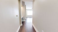 This efficiently designed single-floor home offers a smart, functional layout across a comfortable footprint. The open-concept kitchen and living room serves as the heart of the space, featuring rich dark hardwood flooring, neutral wall tones, and a ceiling fan that enhances airflow and light. The kitchen is outfitted with stainless steel appliances — including a refrigerator, range, and over-the-range microwave — white shaker cabinetry, a decorative tile backsplash, and a dedicated pantry for added storage.

The living area flows naturally from the kitchen, with sunlight reflecting off the hardwood floors and a window providing an inviting brightness. A hallway connects the main living space to the private bedroom, which features plush carpeting, dual windows with blinds that allow ample natural light, and a ceiling fan pendant fixture. The bedroom is generously sized, offering comfortable proportions for furnishing.

The full bathroom is finished with large-format tile flooring, a white vanity with a clean countertop, a framed mirror, and direct access to a walk-in closet equipped with built-in shelving and rack systems. Additional closets and a dedicated laundry area round out the practical amenities. The overall aesthetic is clean, modern, and move-in ready.