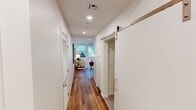 Located at Mainplace Dr in Santa Ana, CA, this thoughtfully designed 2-bedroom, 1-bathroom apartment delivers a modern living experience across a single floor. Rich wood-look flooring flows throughout the main living areas and hallways, complemented by recessed lighting and crisp white walls that create a clean, contemporary aesthetic.

The open kitchen is a standout feature, showcasing warm wood cabinetry, bold black hexagonal tile backsplash, white quartz countertops, a center island, and a full suite of stainless steel appliances. The adjacent living room is bright and welcoming, with a large window framing lush greenery outside, filling the space with natural light.

A hallway with a stylish sliding barn door connects the living areas to the private quarters. The bedrooms are calm and cozy, with plush carpet flooring and soft neutral tones. The primary bedroom offers a comfortable, intimate scale ideal for restful living.

The bathroom is finished in clean white tile with wood-look flooring, a modern vanity with matte black fixtures, a lighted mirror, and a tub-shower combination. Two hallways provide practical flow and access throughout. The overall ambiance is modern and polished, making this apartment a refined urban retreat in the heart of Santa Ana.