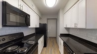 Located at 1480 Runaway Bay Dr in Columbus, Ohio, this single-floor residence offers a well-appointed layout designed for comfortable everyday living. The galley-style kitchen is a standout feature, boasting dark granite countertops, crisp white shaker cabinetry with brushed nickel hardware, a classic subway tile backsplash, and wood-look vinyl flooring. Black appliances, including a range, microwave, refrigerator, and dishwasher, complete the functional cooking space. The open living area flows naturally from the kitchen peninsula, providing a versatile space filled with natural light from large windows. Wood-look flooring extends throughout the main living areas, lending warmth and continuity. The bedrooms are finished with plush carpeting and offer generous proportions, with one featuring a spacious walk-in closet equipped with wire shelving and hanging rods. The bathrooms are thoughtfully updated with white vanity cabinetry, dark granite countertops, undermount sinks, and wood-look flooring. One bathroom includes a full soaking tub and shower combination. A dedicated laundry area with a full-size washer and dryer adds everyday convenience. The overall aesthetic is clean and modern, with a neutral palette throughout.