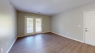 Located at 455 Swiss Ave in Nashville, TN, this single-floor, three-bedroom, two-bathroom home offers a practical and comfortable layout. The open-concept living room is bright and spacious, featuring wood-look laminate flooring and a pair of French doors that invite natural light and provide access to an outdoor area. The kitchen flows seamlessly from the living space and includes white cabinetry, gray laminate countertops, a peninsula with a breakfast bar, and white appliances, creating a clean and functional cooking environment. Two hallways connect the living areas to the private quarters of the home. The three bedrooms are carpeted in neutral tones and feature large windows that bring in natural light, along with ample wall space for furnishings. The generously sized primary bedroom offers a comfortable retreat. Both bathrooms are finished with wood-look flooring, gray countertop vanities with under-sink storage, and mirrors. One bathroom includes a full soaking tub and shower combination with chrome fixtures. Throughout the home, a consistent neutral gray color palette on the walls ties the spaces together, lending a calm and cohesive aesthetic suited for a variety of interior styles.