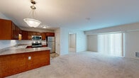 This single-floor residence offers three bedrooms and two bathrooms within a efficiently organized layout. The open-concept kitchen and living area serves as the heart of the unit, where the kitchen features rich warm-toned wood cabinetry, granite-look laminate countertops, stainless steel appliances including a range, microwave, refrigerator, and dishwasher, and a peninsula that provides additional counter space while visually connecting to the living area. Stone-tile flooring anchors the kitchen, transitioning to neutral wall-to-wall carpet throughout the living and bedroom areas.

The living room receives natural light through a large sliding glass door dressed with vertical blinds. The primary bedroom offers a walk-in closet with built-in shelving and direct access to one of the two bathrooms. The bathrooms are finished with wood-tone vanities, white countertops, brushed nickel fixtures, and stone-tile flooring; one bathroom includes accessibility grab bars and a sliding-door shower enclosure. The additional bedrooms are carpeted and feature neutral walls with ample natural light. Throughout the unit, a clean, neutral color palette creates a cohesive and functional living environment.
