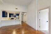 Located in Atlanta's Grant Park neighborhood, this 2-bedroom, 2-bathroom residence offers a well-designed layout across a single floor. The open-concept living and kitchen area immediately impresses with soaring ceilings that amplify the sense of space. Rich hardwood floors run throughout the main living areas, complementing the clean white walls and modern finishes.

The kitchen is a standout feature, showcasing bold navy cabinetry with sleek hardware, a herringbone tile backsplash, white quartz countertops, and stainless steel appliances including a refrigerator, range, and microwave. A peninsula counter provides additional workspace and serves as a natural divider between the kitchen and living area.

The primary bedroom is generously sized, offering tall ceilings, a ceiling fan, large multi-pane windows that fill the room with natural light, and tranquil views of surrounding greenery. The second bedroom is carpeted and similarly bathed in natural light through expansive windows with outdoor views. Both bathrooms are clean and functional, each featuring a soaking tub and shower combination — one with a navy vanity echoing the kitchen's design palette. A dedicated closet adds practical storage to complete the layout.