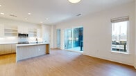This well-designed single-floor residence offers two bedrooms and two bathrooms within a thoughtfully laid-out floor plan. The open-concept kitchen and living area serves as the heart of the home, featuring light hardwood flooring, recessed lighting, and a seamless flow between spaces. The kitchen is appointed with stainless steel appliances, a built-in microwave, white upper cabinetry with open shelving, warm wood lower cabinets, and a peninsula with a clean white countertop — ideal for dining or meal preparation.

The living area opens directly onto an outdoor balcony through full-width sliding glass doors, filling the space with natural light and providing city skyline views. The primary bedroom, a well-proportioned space, also benefits from sliding glass door balcony access and an additional window, further enhancing natural light. Both bedrooms feature neutral carpet flooring and ceiling fans. Each bedroom is served by a dedicated closet with built-in shelving, hanging rods, drawers, and shoe storage.

The bathrooms are finished in a modern style, featuring wood-toned floating vanities, white countertops, matte black fixtures, glass-enclosed showers, and hardwood-style flooring, creating a clean and cohesive aesthetic throughout the residence.