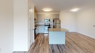 Located at 2778 2nd St NE in Hickory, North Carolina, this single-floor residence offers a well-designed open-concept layout with modern finishes throughout. The kitchen serves as a focal point of the living space, outfitted with gray shaker-style cabinetry, granite countertops, and a full suite of stainless steel appliances including a refrigerator, electric range, microwave, and dishwasher. A granite-topped island provides additional prep space and opens seamlessly into the main living area, which features durable wood-look flooring, crown molding, and a ceiling fan. Sliding glass doors lead to an outdoor balcony, allowing natural light to fill the living space and offering views of the surrounding greenery. The bedroom is carpeted for comfort and maintains the clean, neutral palette found throughout the unit. The bathroom is finished with wood-look flooring, a granite vanity countertop, brushed nickel fixtures, and a full tub-shower combination with tile surround. Crisp white walls and consistent trim details create a cohesive, move-in-ready aesthetic across all rooms.