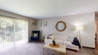This single-floor residence at 1423 Preston Ridge St NW in Walker, Michigan, offers a well-organized layout across several distinct functional areas. The living room serves as the central gathering space, featuring neutral-toned carpet, soft natural light, and a large sliding glass door fitted with vertical blinds that opens to an outdoor view of surrounding greenery. A wall-mounted air conditioning unit provides climate control, and the room's understated palette creates a calm, versatile backdrop.

The galley-style kitchen is efficiently arranged with dark espresso cabinetry lining both sides, light-toned countertops, wood-look vinyl flooring, and white appliances including a gas range, refrigerator, and overhead microwave. A chalkboard-painted door adds a distinctive functional accent.

The bedroom is generously proportioned with plush carpeting, a window overlooking tree coverage, and a baseboard heating unit. The room accommodates both sleeping and workspace areas comfortably, offering a quiet and practical environment.

The bathroom features wood-look flooring, a full tub and shower combination with a curtain surround, and clean, neutral finishes throughout. The overall ambiance of the unit is quiet and functional, with consistent neutral tones and practical features throughout each space.