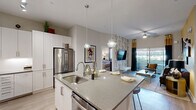Located along North Scottsdale Road in the heart of Scottsdale, Arizona, this thoughtfully designed 2-bedroom, 2-bathroom residence offers a seamless blend of modern style and functional living. The open-concept floor plan connects the kitchen, dining, and living areas into a cohesive, airy space bathed in natural light.

The kitchen is a standout, featuring crisp white cabinetry extending to the ceiling, quartz countertops, a large center island with a undermount sink, stainless steel appliances including a gas range and French door refrigerator, and elegant globe pendant lighting.

The living room showcases bold, botanical-patterned accent wallpaper, rich hardwood-style flooring, a ceiling fan, and sliding glass doors that open to a private balcony with outdoor views — an ideal setting for Scottsdale's sunny climate.

The primary bedroom is a serene retreat with a striking geometric accent wall, plush carpet, a ceiling fan, and generous natural light. The second bedroom is equally well-appointed with bright windows and warm, neutral tones. Both bedrooms benefit from dedicated closet space, and three total closets provide excellent storage throughout.

The bathrooms are finished with quartz-topped vanities and backlit mirrors. A dedicated laundry room with side-by-side washer and dryer completes this well-appointed residence.