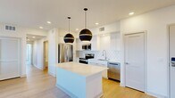Located in Palm Desert, CA, this thoughtfully designed 2-bedroom, 2-bathroom residence offers a well-appointed single-floor layout. The open-concept kitchen serves as the heart of the home, showcasing a striking waterfall quartz island beneath a pair of bold matte black globe pendant lights. White shaker-style cabinetry extends to the ceiling, complemented by a geometric tile backsplash and a full suite of stainless steel appliances, including a French door refrigerator, range, microwave, and dishwasher. Light wood-look flooring flows seamlessly throughout the main living area, enhancing the bright, airy atmosphere created by recessed lighting and natural light from multiple windows. A private balcony offers outdoor access directly from the living space. The spacious primary bedroom features a ceiling fan, hardwood-style flooring, and a dedicated balcony access door. The secondary bedroom is carpeted and includes a built-in closet with shelving. Both bathrooms are finished with clean white cabinetry, undermount sinks, large mirrors, and tub-shower combinations with tile surrounds. The residence also includes a dedicated closet for additional storage, rounding out a functional and modern living space.