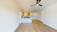 This well-appointed 2-bedroom, 3-bathroom residence at 701 Saginaw Blvd in Saginaw, TX offers a thoughtfully designed single-floor layout with a clean, contemporary aesthetic throughout. Light wood-tone flooring flows seamlessly across the open-concept living and kitchen area, creating a bright and cohesive feel. The kitchen is a standout feature, showcasing a two-tone design with white upper cabinetry and warm natural wood lower cabinets, complemented by a subway tile backsplash, white quartz countertops, a peninsula with a sink, and a full suite of stainless steel appliances including a range, microwave, dishwasher, and French door refrigerator. Sleek black pendant lighting adds a modern touch overhead. The living area is spacious and airy, equipped with a ceiling fan and access to a private balcony through sliding glass doors. Both bedrooms are generously sized, featuring the same warm flooring, ample closet space, and clean white walls. The primary bedroom connects to an en suite bathroom with a glass-enclosed walk-in shower finished in neutral tile. Additional bathrooms include a full bath with a soaking tub and wood-toned vanity cabinetry with black fixtures. Four closets provide excellent storage throughout.