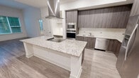 Located at 350 Village Drive in King of Prussia, PA, this thoughtfully designed 2-bedroom, 2-bathroom residence offers a comfortable and modern living experience across a single floor. The open-concept kitchen is a standout feature, showcasing dark wood-grain cabinetry, stainless steel appliances including a built-in oven, microwave, dishwasher, and French door refrigerator, all complemented by a large granite-topped island with a sleek island hood. Light wood-style flooring ties the kitchen and adjacent living areas together seamlessly. The primary bedroom is generously sized, featuring an elegant tray ceiling with a ceiling fan and plush carpeting. It connects to a spacious walk-in closet with built-in wire shelving and a luxurious en-suite bathroom appointed with marble-style tile, a soaking tub, a glass-enclosed shower, granite countertops, and dark wood vanity cabinetry. The second bedroom also features a tray ceiling, ceiling fan, carpeted floors, and a large window overlooking lush greenery. The second bathroom mirrors the refined finishes found throughout, with marble tile flooring, a granite vanity, and gold-framed mirror. Two well-sized closets provide ample storage throughout the residence.