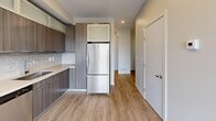 This thoughtfully designed one-bedroom, two-bathroom unit in Calgary offers a smart and efficient layout across a single floor. Light-toned wood-look flooring runs continuously throughout, complementing the clean, neutral palette of the walls and trim.

The open-concept living, dining, and kitchen area forms the heart of the unit. The kitchen is well-appointed with dark wood-grain cabinetry, frosted upper cabinets, a subway tile backsplash, light quartz countertops, and a full suite of stainless steel appliances including a refrigerator, range, microwave, and dishwasher. Large windows in the living area flood the space with natural light and offer views of the surrounding neighbourhood, while a glass-panel door leads directly to the balcony.

The bedroom is a bright, cozy retreat featuring a window with an outdoor view and ample closet storage. Three closets in total provide generous storage throughout the unit. A versatile den offers additional flexible space for a home office or guest area.

Both bathrooms are finished in a modern style with dark wood-grain vanities and light countertops. One features a glass-enclosed shower, while the other includes a full soaker tub. In-suite laundry adds everyday convenience, and a welcoming entrance completes this well-appointed home.