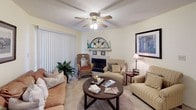 Located at 1500 Champions Pines Ln in Augusta, Georgia, this single-story residence offers a well-organized and comfortable layout throughout. The living room serves as the heart of the home, featuring a classic fireplace with a decorative mantle, plush carpeted flooring, a ceiling fan, and large vertical-blind-covered sliding doors that allow natural light to fill the space. The kitchen is efficiently designed with ample warm-toned wood cabinetry, generous counter space, a stainless steel sink, and hardwood-style flooring, providing a practical and inviting cooking environment. The primary bedroom is a spacious and serene retreat, complete with soft carpeting, a walk-in closet, and direct access to an en-suite vanity area with Hollywood-style lighting and an adjoining full bathroom. The bathroom features tile flooring, a separate walk-in shower, a soaking tub with shower combination, and a vanity with sink. A second bedroom offers a bright, comfortable space with a window that brings in natural light. Throughout the home, neutral wall tones and soft finishes create a warm and cohesive ambiance, making this residence a practical and inviting single-floor home in Augusta.
