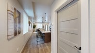 Located in Coeur d'Alene, Idaho, this thoughtfully designed two-story home offers three bedrooms, three bathrooms, a dedicated office, and a laundry room across two well-appointed floors. The main level welcomes you with light-toned wood-look flooring that flows through an open-concept living, dining, and kitchen area. The kitchen is a standout feature, boasting rich taupe cabinetry, stainless steel appliances, a large white quartz waterfall island with bar seating, and stylish pendant lighting overhead. A well-organized pantry with wire shelving provides ample storage. The office receives abundant natural light through oversized windows, making it an ideal workspace. Upstairs, the primary bedroom is generously proportioned, complemented by carpeted flooring and its own bathroom. Two additional bedrooms share access to well-appointed bathrooms, each featuring wood-toned vanities with white countertops, tile-style flooring, and natural light from vertical-blind windows. A clean, neutral hallway with crisp white panel doors and dark hardware connects the upper-level rooms. Throughout the home, a consistent modern aesthetic is maintained with neutral tones, recessed lighting, and quality finishes that create a bright, welcoming ambiance.