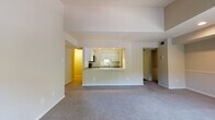 This single-floor residence is designed with an open, functional layout that connects the living spaces in a cohesive and practical manner. The generously sized living room is carpeted and features a tile-surround fireplace with a classic white mantel, lending a warm focal point to the space. Elevated ceilings add a sense of volume and openness throughout the main living area.

The kitchen is accessible via a pass-through counter that opens directly to the living room, creating a connected feel ideal for everyday living. White cabinetry provides ample storage, while stainless steel appliances—including an electric range and over-the-range microwave—add a modern, functional touch. Light countertops complement the clean, neutral palette.

The primary bedroom is spacious and carpeted, offering access to a dedicated en-suite bathroom and a walk-in closet with built-in shelving. Additional bedrooms are also well-sized with carpeted floors and closet access. The bathrooms are finished with warm-toned tile surrounds, soaking tubs, sliding glass shower enclosures, and wood-look flooring, offering a clean and comfortable aesthetic throughout.