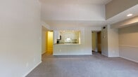 This single-floor residence is designed with an open, functional layout that connects the living spaces in a cohesive and practical manner. The generously sized living room is carpeted and features a tile-surround fireplace with a classic white mantel, lending a warm focal point to the space. Elevated ceilings add a sense of volume and openness throughout the main living area.

The kitchen is accessible via a pass-through counter that opens directly to the living room, creating a connected feel ideal for everyday living. White cabinetry provides ample storage, while stainless steel appliances—including an electric range and over-the-range microwave—add a modern, functional touch. Light countertops complement the clean, neutral palette.

The primary bedroom is spacious and carpeted, offering access to a dedicated en-suite bathroom and a walk-in closet with built-in shelving. Additional bedrooms are also well-sized with carpeted floors and closet access. The bathrooms are finished with warm-toned tile surrounds, soaking tubs, sliding glass shower enclosures, and wood-look flooring, offering a clean and comfortable aesthetic throughout.