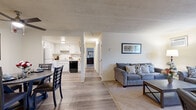 This single-floor unit offers a thoughtfully arranged layout that balances functionality and comfort throughout. The open-concept living and dining area serves as the heart of the space, with light wood-style flooring that flows seamlessly from the living room toward the kitchen. The living room features carpet underfoot, a large window with vertical blinds that allows natural light to fill the room, and a wall-mounted air conditioning unit. A dedicated dining area, just off the kitchen, includes a ceiling fan with light fixture and connects comfortably to the main living space.

The kitchen is outfitted with white cabinetry, a tile backsplash, ample counter space, a built-in dishwasher, and a refrigerator — offering a clean and practical cooking environment.

A carpeted hallway connects the private areas of the unit, leading to two well-sized bedrooms, each featuring plush carpet, large windows with vertical blinds, and baseboard heating. Both rooms offer a calm, restful atmosphere with generous natural light.

A flexible bonus room functions as a dedicated office or study space, complete with a pendant light fixture and wood-style flooring, making it well-suited for work or focused activities. Throughout, the unit maintains a neutral, cohesive palette that creates a clean and welcoming ambiance.