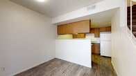 This two-floor residence offers a practical and well-organized layout designed for comfortable everyday living. The kitchen is equipped with warm oak cabinetry lining both walls, white appliances including an electric range and dishwasher, light-toned countertops, and hardwood-style flooring. A half-wall partition separates the kitchen from the adjacent living area, which also features the same durable hardwood-style flooring and a textured ceiling. The bedrooms are carpeted for comfort and include ceiling fans with light fixtures, natural light from windows with vertical blinds, and ample wall space. The two bathrooms are finished with speckled granite-look countertops, oak vanity cabinetry, large wall mirrors, and clean white fixtures. One bathroom includes a shower-tub combination, while the other provides additional utility with in-unit washer and dryer hookups nearby. Textured ceilings are consistent throughout the home. The overall layout, as visible in the dollhouse view, is compact yet efficiently arranged, making good use of the available space across both floors. The neutral color palette of whites and beiges creates a clean, cohesive atmosphere throughout the residence.