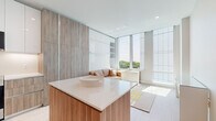 Located at 2100 N Central Rd in Fort Lee, NJ, this thoughtfully designed studio unit delivers a clean, modern aesthetic within a compact, efficiently laid-out single-floor plan. The open-concept living area is immediately striking, bathed in abundant natural light streaming through expansive floor-to-ceiling windows that frame lush treetop views. Light-toned hardwood flooring runs throughout, reinforcing the bright, airy atmosphere.

The kitchen is a standout feature, showcasing a sophisticated blend of high-gloss white upper cabinetry and warm wood-grain lower cabinets and panels. A sleek white quartz island with bar seating serves as both a functional workspace and a visual centerpiece. Stainless steel appliances and under-cabinet lighting complete the polished look.

A full-height wood-paneled wall with integrated storage and a Murphy bed provides smart, space-saving functionality in the living area, where a cozy seating nook nestles against the window wall to take full advantage of the outdoor views.

The bathroom is finished with marble-style wall tile, large-format floor tiles, a wood-fronted floating vanity with a white quartz countertop, and a glass-enclosed shower — all contributing to an upscale, spa-like feel. Overall, the space achieves an elegant balance of modern design and practical living.