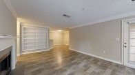 Located at 9200 Roberts Dr. in Sandy Springs, GA, this single-story residence offers a well-designed layout with a cohesive, neutral color palette throughout. The open living and dining area is highlighted by rich wood-look flooring, crown molding, and a ceiling fan with light fixture. A chandelier illuminates the dining space, which connects seamlessly to the living area through an open-concept flow. A built-in shelving unit adds functional character to the living room, while a private exterior door and large windows invite abundant natural light and views of surrounding greenery.

The galley-style kitchen is equipped with dark espresso cabinetry, light stone-look countertops, a tile backsplash, and stainless steel appliances including a range and dishwasher. A pass-through counter opening connects the kitchen to the main living area. Bedrooms feature plush carpeting, ceiling fans, and windows overlooking the wooded surroundings. The bathroom includes a full soaking tub with white tile surround, adding a clean, classic finish. Throughout the space, consistent trim work, textured ceilings, and warm tones create a comfortable and well-maintained living environment.