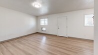 Located at 701 E Pennington St in West Burlington, Iowa, this 2-bedroom, 1-bathroom unit offers a clean, functional layout across a single floor. Light wood-style flooring runs throughout the entire space, providing a cohesive and bright aesthetic complemented by crisp white walls and textured ceilings.

The combined kitchen and living area forms the heart of the unit. The kitchen features white shaker-style cabinetry, light quartz countertops, stainless steel appliances including a refrigerator and electric range, and a window that brings in natural light. The adjacent living area is open and spacious, with multiple windows, a front entry door, and a wall-mounted heating unit.

The primary bedroom offers comfortable accommodations with two closets, a wall shelf, and a ceiling vent, providing ample storage. The second bedroom is bright and airy, with a window fitted with blinds and easy access to the hallway. A connecting hallway links the bedrooms to the full bathroom, which includes a vanity with storage, a toilet, and a shower-tub combination with built-in shelving.

The unit's consistent use of light tones, wood-style flooring, and white finishes throughout creates a clean, move-in-ready atmosphere well-suited for comfortable everyday living.