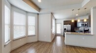 Located at 1639 Cable Ranch Rd in San Antonio, Texas, this two-story residence offers a thoughtfully designed layout spread across two levels. The main living area is open and airy, anchored by warm hardwood-style flooring and a striking bay window configuration that floods the space with natural light. A neutral color palette enhances the bright, welcoming ambiance throughout.

The kitchen is a standout feature, boasting rich dark cabinetry, granite countertops with a complementary tile backsplash, and a full suite of stainless steel appliances including a side-by-side refrigerator with ice maker, a gas range with microwave above, and a large peninsula ideal for casual dining or meal prep. Pendant lighting adds a refined touch overhead.

The bedrooms are carpeted for comfort, offering a soft contrast to the hard flooring in the main living areas. The primary bathroom is well-appointed with a dual-sink vanity topped with granite, dark cabinetry, and a large mirror. A separate tiled tub-shower combo provides a clean, modern finish. A generously sized walk-in closet with built-in wire shelving provides ample storage. The lower level includes a large unfinished garage space, offering significant utility and storage potential.