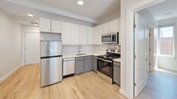 Located at 72 Burbank St in Boston's vibrant Fenway neighborhood, this efficiently designed one-bedroom, one-bathroom unit offers a well-planned layout across a single floor. Light hardwood flooring flows throughout, creating a cohesive and bright aesthetic.

The kitchen is a standout feature, outfitted with a full suite of stainless steel appliances including a refrigerator, electric range, over-the-range microwave, and dishwasher. White upper cabinetry is paired with gray lower cabinets and light countertops, maximizing storage while maintaining a clean, modern look. Recessed lighting and light wood-tone flooring enhance the space's openness.

The bedroom is an intimate yet functional retreat, benefiting from two windows that invite natural light and offer views of the surrounding brick architecture. Neutral walls and light flooring keep the room feeling airy and versatile.

The bathroom is finished with elegant large-format marble-look tile flooring, a dark-toned vanity with a white countertop, and a wall-mounted heated towel rack, adding a refined touch. White panel doors and warm neutral wall tones unify the overall interior design. This unit offers a practical and polished urban living space in the heart of Boston.
